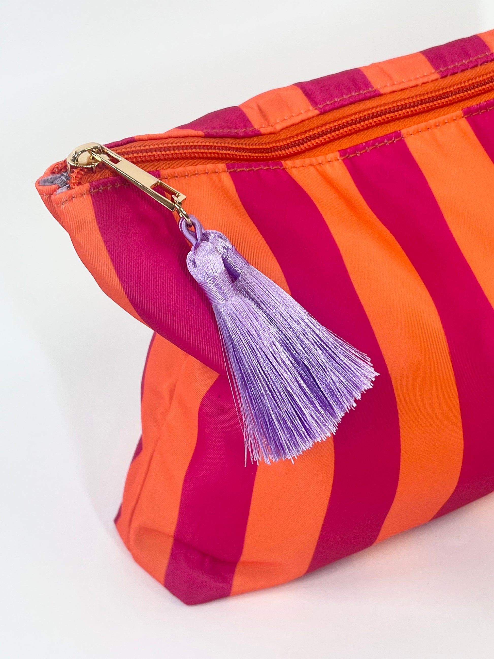 Striped pouch with a purple tassel on a light background