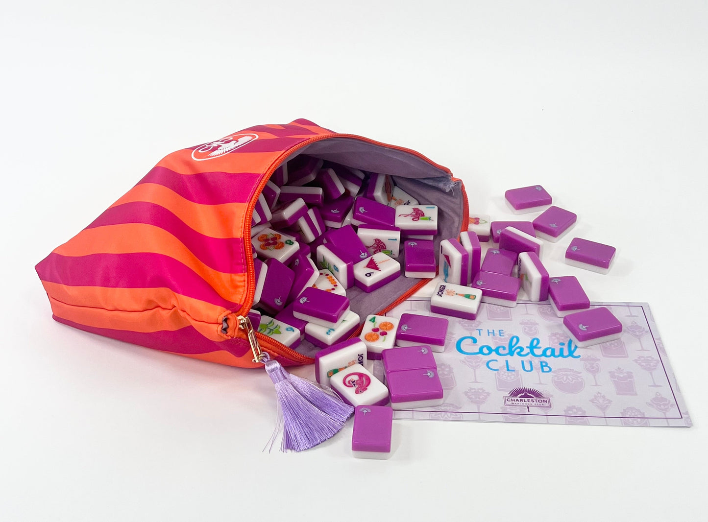Purple and orange striped bag with mahjong tiles and a card labeled 'The Cocktail Club' on a white background