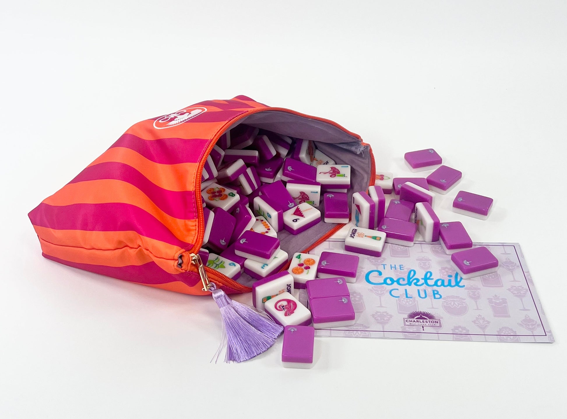 Purple and orange striped bag with mahjong tiles and a card labeled 'The Cocktail Club' on a white background
