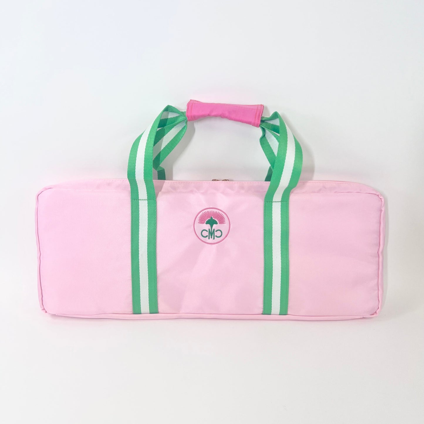 Pink rack bag with green/ white striped straps on a white background