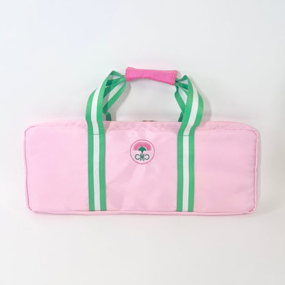 Pink rack bag with green/ white striped straps on a white background