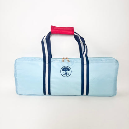 Light blue rack bag with navy stripes and a red handle on a white background