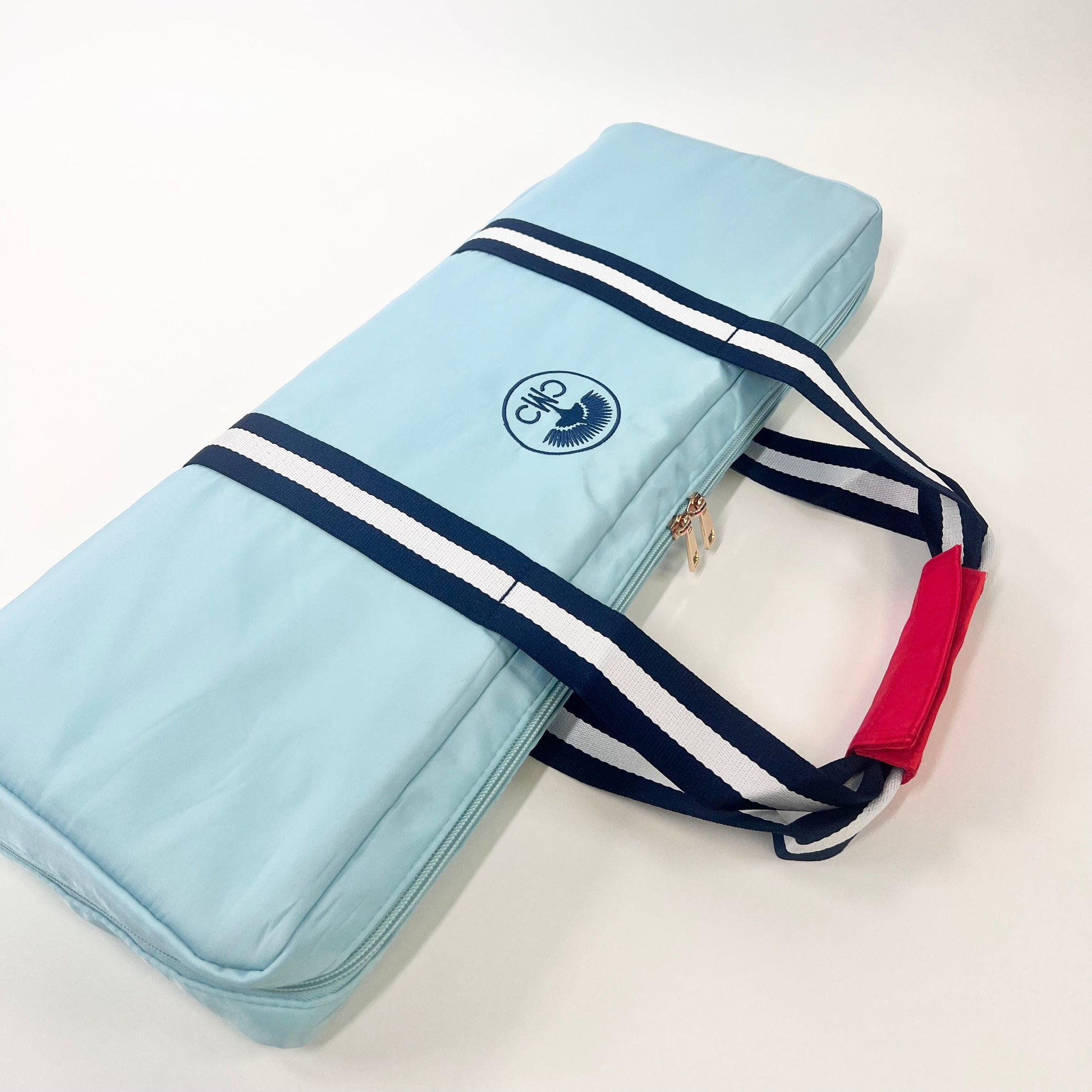 Light blue rack bag with navy and white striped strap on a white background