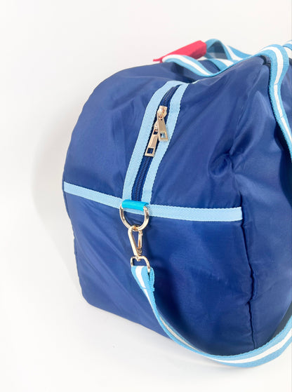 Blue duffel bag with white trim on a white background