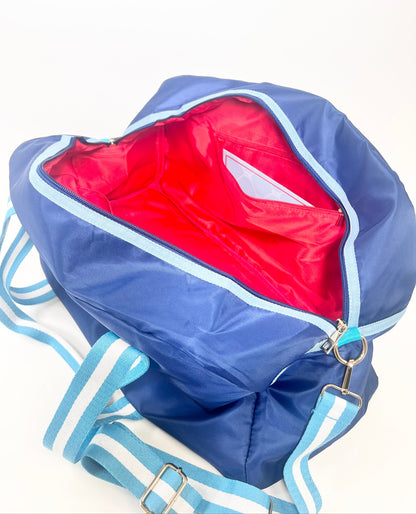 Blue duffel bag with red interior on a white background