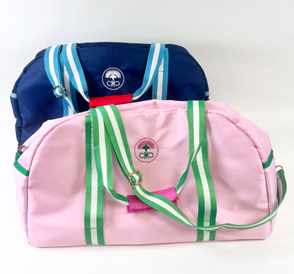 Pink duffel bag with green straps and a blue duffel bag with light blue straps on a white background
