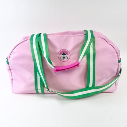 Pink duffel bag with green and white straps with visible logo on a white background