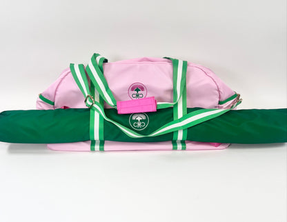 Pink and green bag with mat bag slid through straps on the front on a white background