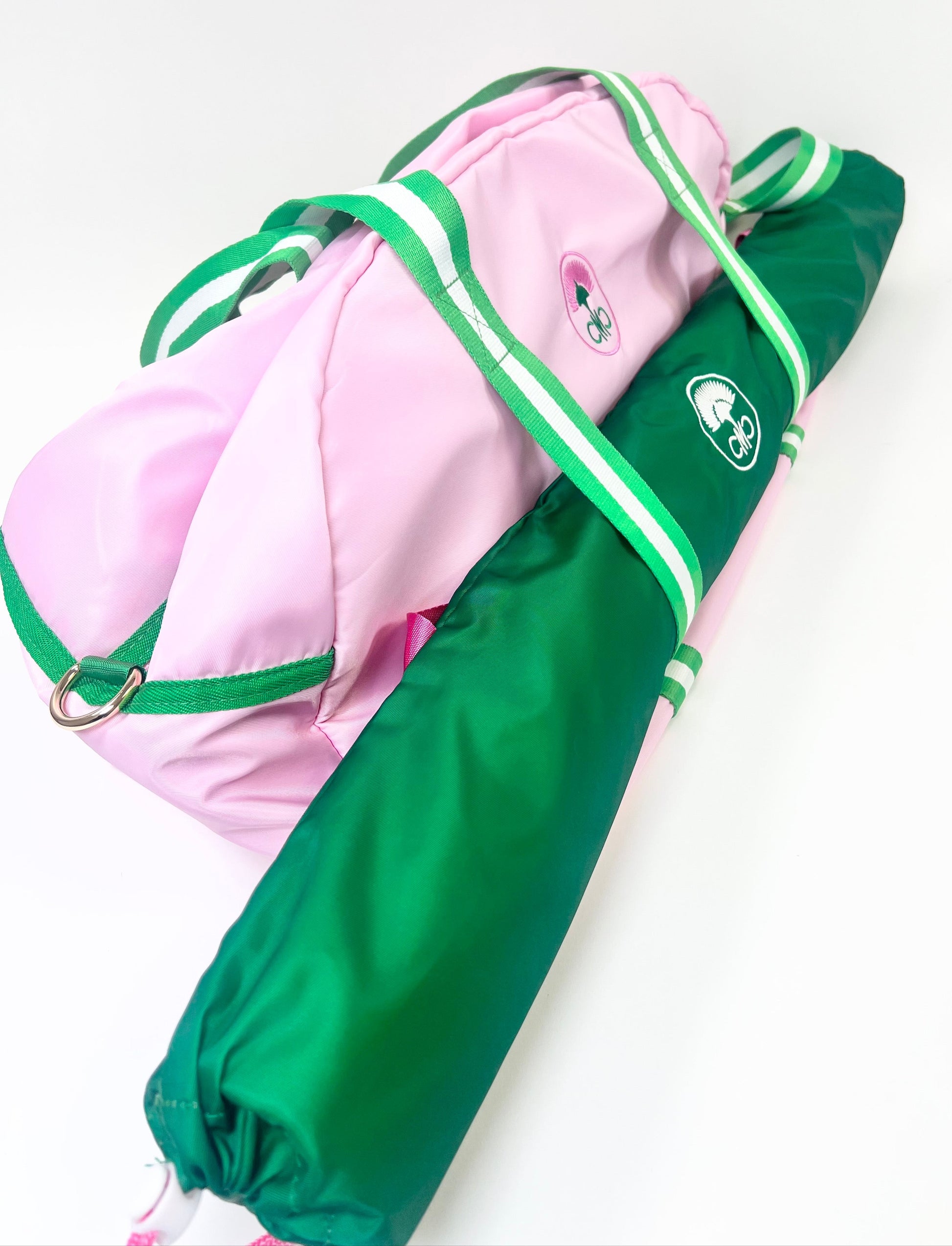 Pink and green duffel with mat bag attached to the front with a logo on a white background